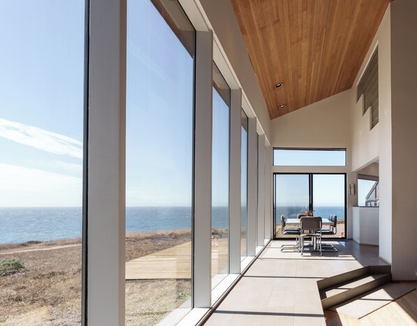 A modern interior with large windows overlooking a coastal view.
