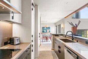 A modern kitchen with a built-in toaster, a sink, and a dining area with red chairs.