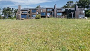 Une maison moderne à plusieurs étages, dotée d’un toit plat, de grandes fenêtres et d’une cour gazonnée.