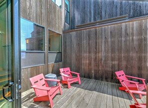 A room with a wooden floor, a sliding glass door, and three red chairs.