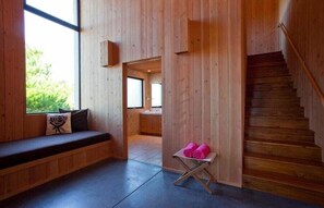 A wooden interior with a bench, a small table with towels, and a staircase. - Horizon Reach - Black Point Beach Views (Sea Ranch)
