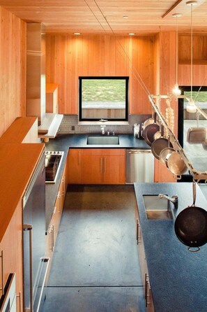 A modern kitchen with wooden cabinetry, a large window, and a built-in television.