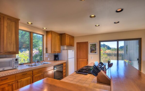 A kitchen with wooden cabinets, a microwave, a sink, and a countertop with knives.