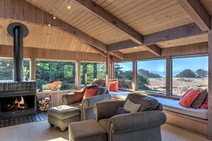 A cozy living room with a fireplace, large windows, and comfortable seating.