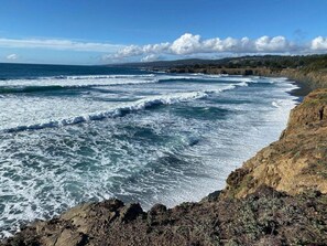 A coastal landscape with waves crashing onto a rocky shore.