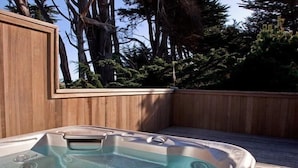 A hot tub on a wooden deck with a view of trees.