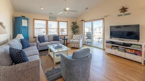 Een woonkamer met een bank, fauteuil, salontafel, tv-meubel en een klok.