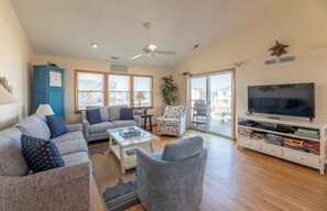 A living room with a sofa, armchair, coffee table, TV stand, and a clock.