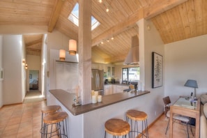 A spacious kitchen with a central island, bar stools, and a dining area with a table and chairs.