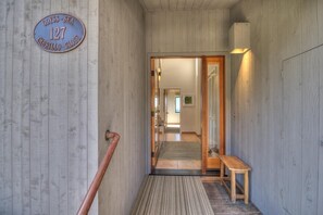 A hallway with a wooden floor, a bench, and a door leading to another room.