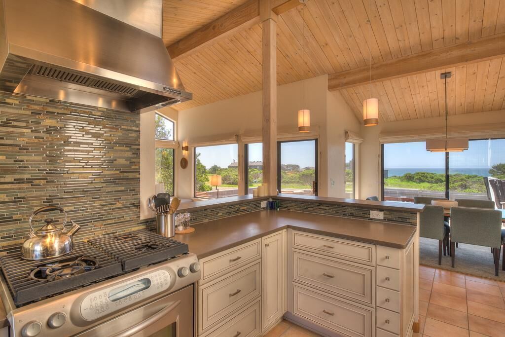 A modern kitchen with a large island, stainless steel appliances, and a view of the outdoors.