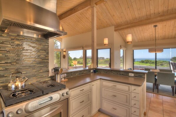 A modern kitchen with a large island, stainless steel appliances, and a view of the outdoors.