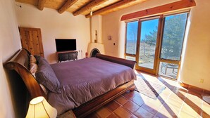 A bedroom with a large bed, wooden ceiling beams, a television, and a view of the outdoors through a sliding door. - Casa Luminosa, Private Hot Tub Los Altos Clubhouse with pool, sauna, tennis (Arroyo Seco)
