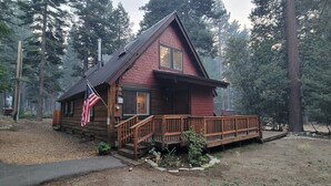 Een blokhut met een houten terras, een Amerikaanse vlag en een bebost achtergrond.