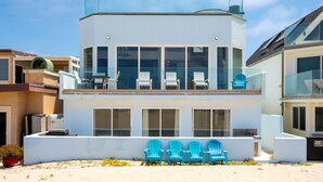 A modern two-story building with large windows and a balcony with blue chairs. - 3525O - Big Blue Beauty: 3  BR, 5  BA House in Oxnard, Sleeps 6 (Oxnard)