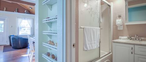 Un baño con ducha, lavamanos y espejo. Hay una toalla colgada en la pared.