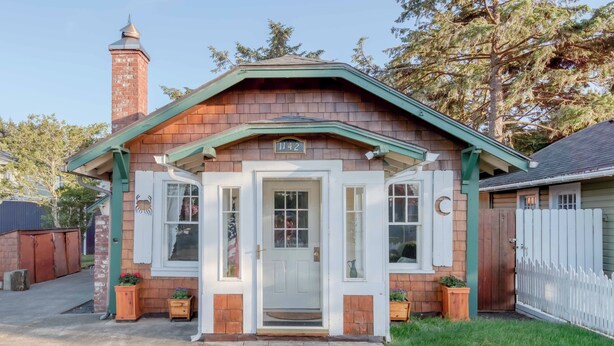 Een tweelaags huis met schoorsteen, een veranda en een brievenbus.