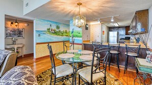 A dining area with a glass table, metal chairs, and a chandelier. - Horizon East 804 - Two Bedroom, Two Bath Oceanfront Condo (Garden City Beach)