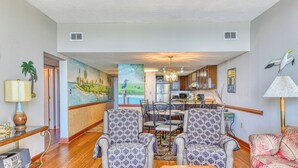 A spacious living room with patterned armchairs, a wooden coffee table, and a vibrant mural on the wall. - Horizon East 804 - Two Bedroom, Two Bath Oceanfront Condo (Garden City Beach)