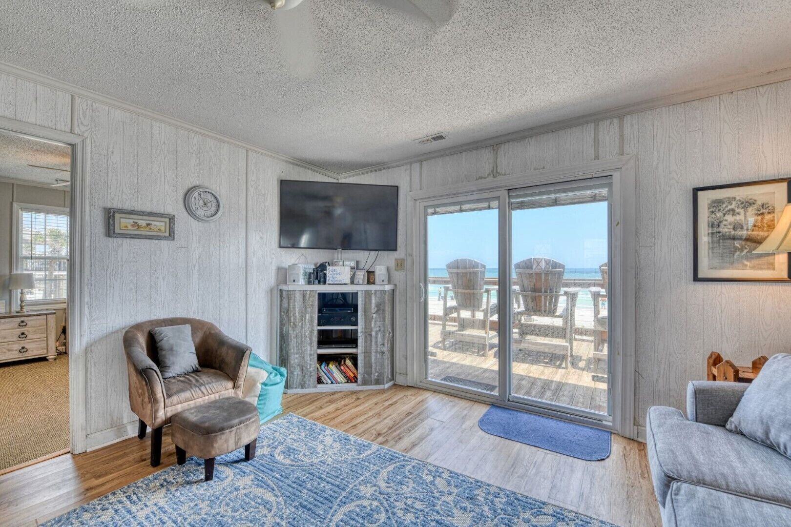 A spacious living room with a large sliding glass door leading to a balcony with beach chairs.