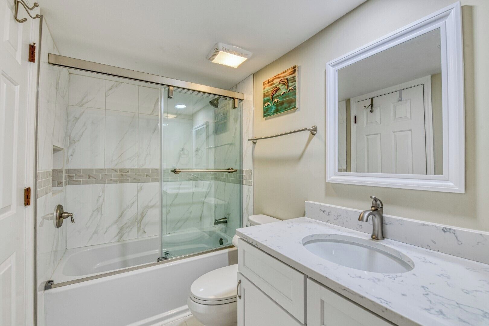 A bathroom with a glass-enclosed shower, two sinks, and a large mirror.