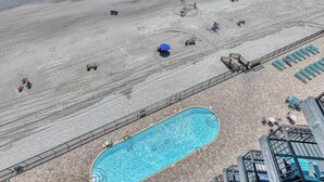 En vy över en strand från ovan, med en swimmingpool, solstolar och ett inhägnat område.