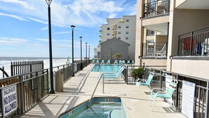 A pool area with a 3 FT depth sign, lounge chairs, and a view of the beach. - Corner Unit - Breathtaking Views  - Great Condition (Garden City Beach)