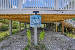 Um deck de madeira com uma placa que diz 'Love a Beach' e o número '1387' no corrimão.