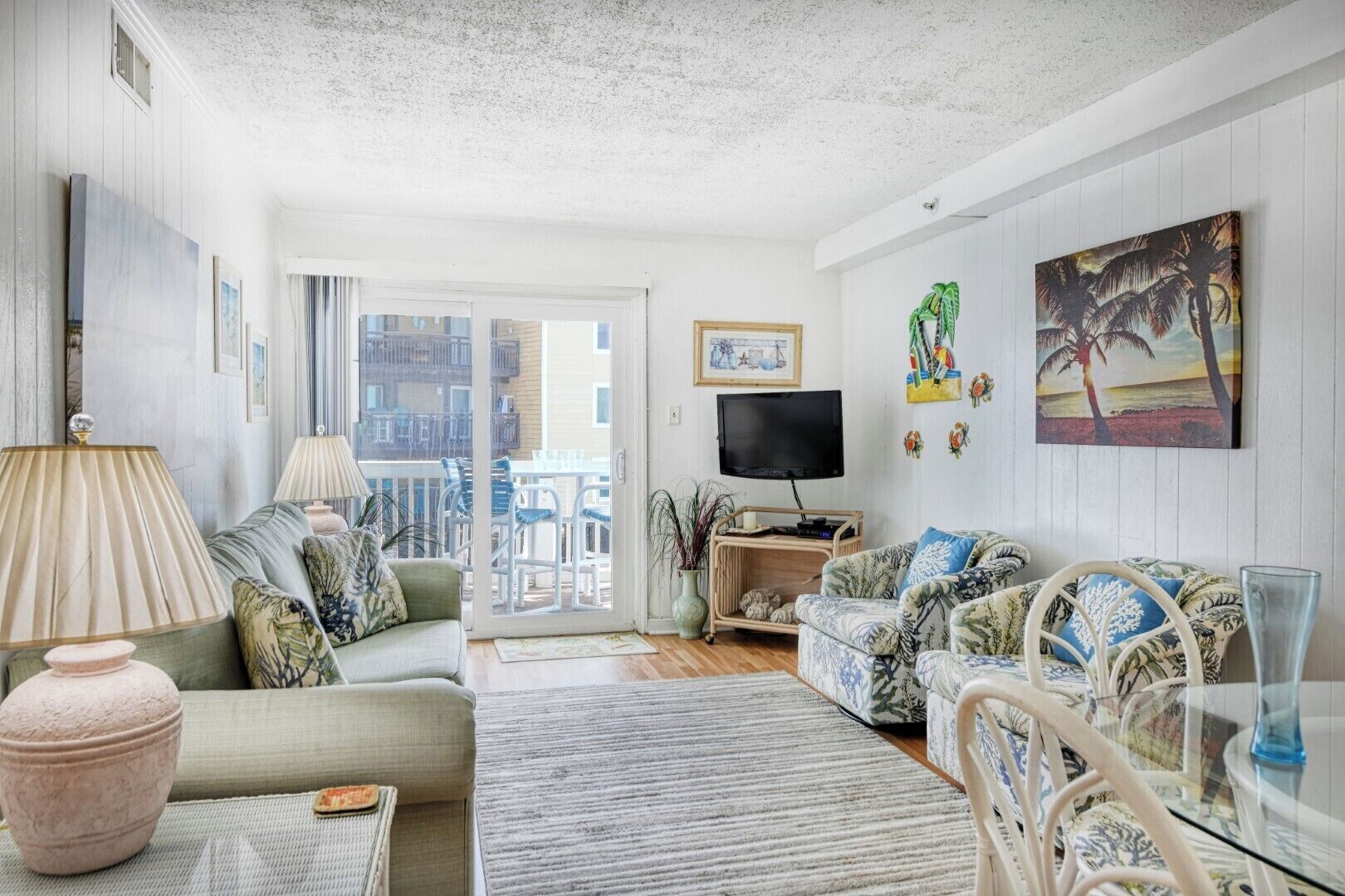Un salon avec un canapé, un téléviseur et un balcon aménagé avec du mobilier d’extérieur.