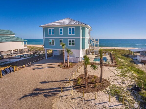Un bâtiment à deux étages avec vue sur la plage, une piscine et un poste de surveillance pour les sauveteurs.