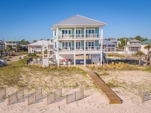 A two-story beach house with a covered porch and a wooden deck leading to the entrance. - THE WAIT IS OVER!  PAPAW'S SANDBOX IS READY! (St. George Island)