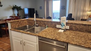 Una cocina con encimeras de granito, electrodomésticos de acero inoxidable y vistas al océano a través de amplias ventanas.