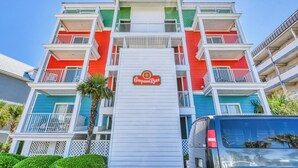 A multi-story hotel with balconies, a central sign, and a parking area. - Compass Rose 11, three-bedroom, two-bath condo, ocean front (Garden City Beach)