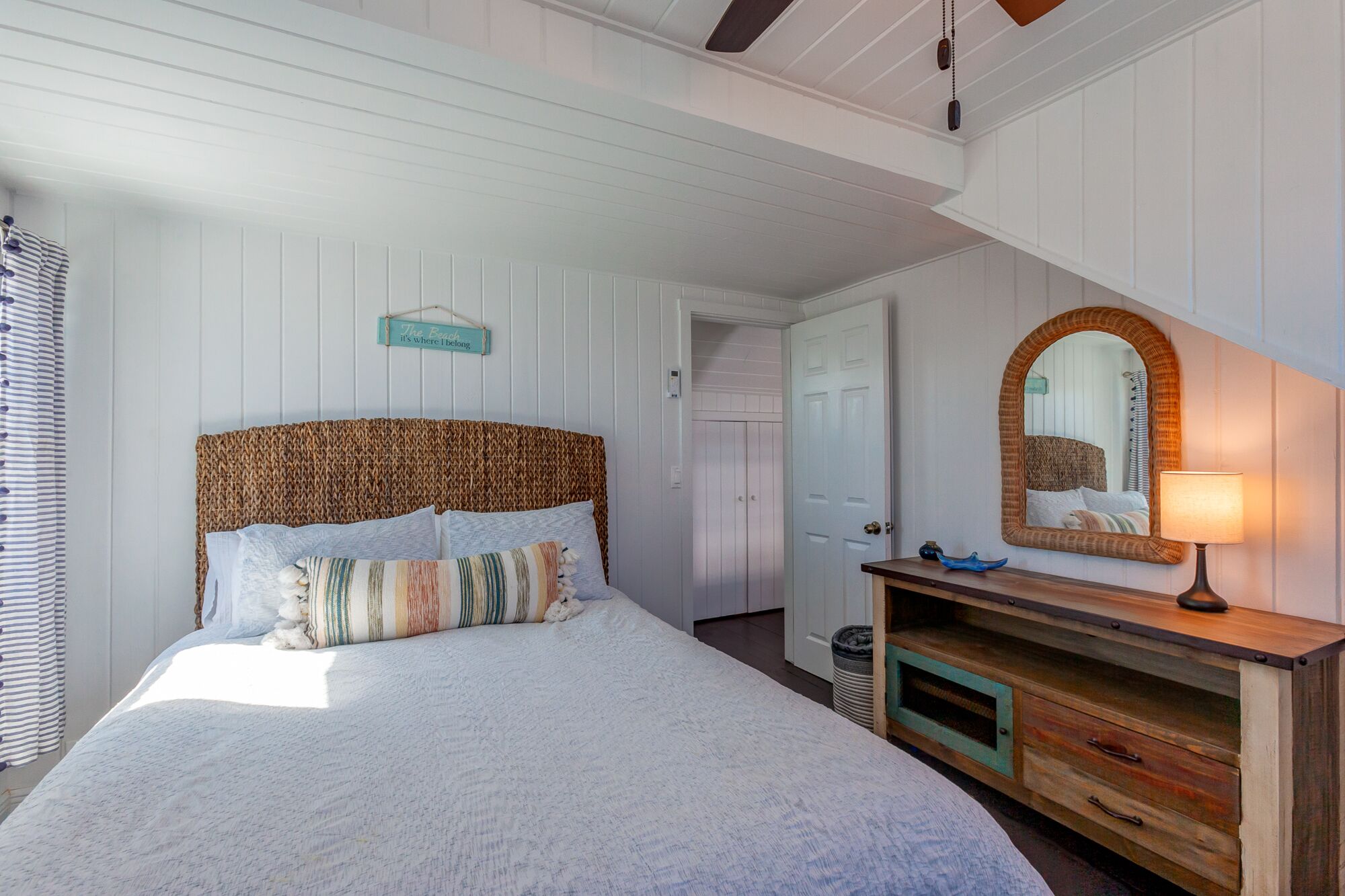 Un dormitorio con una cama grande, un aparador de madera, un espejo y un letrero en la pared.