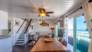 A nautical-themed living room with a wooden dining table, a large fish decoration, and a view of the ocean. - High Hopes: Charming Oceanfront Cottage on the North End of Elbow Cay (Elbow Cay)