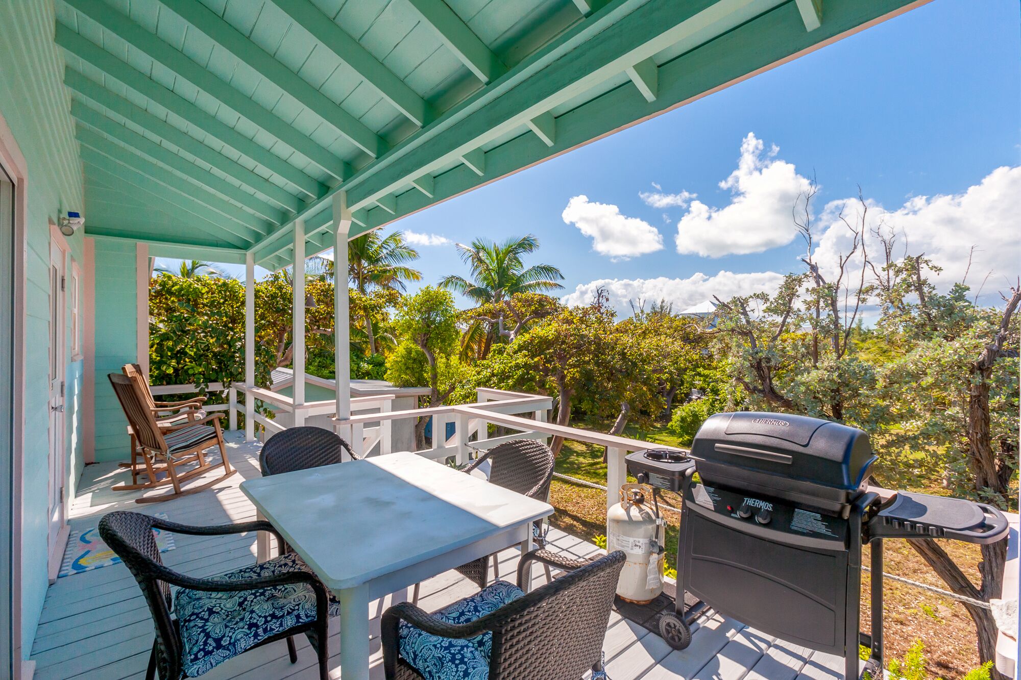 An outdoor patio with a table, chairs, and a grill.