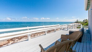 A wooden deck with white railings overlooking a beach. - High Hopes: Charming Oceanfront Cottage on the North End of Elbow Cay (Elbow Cay)