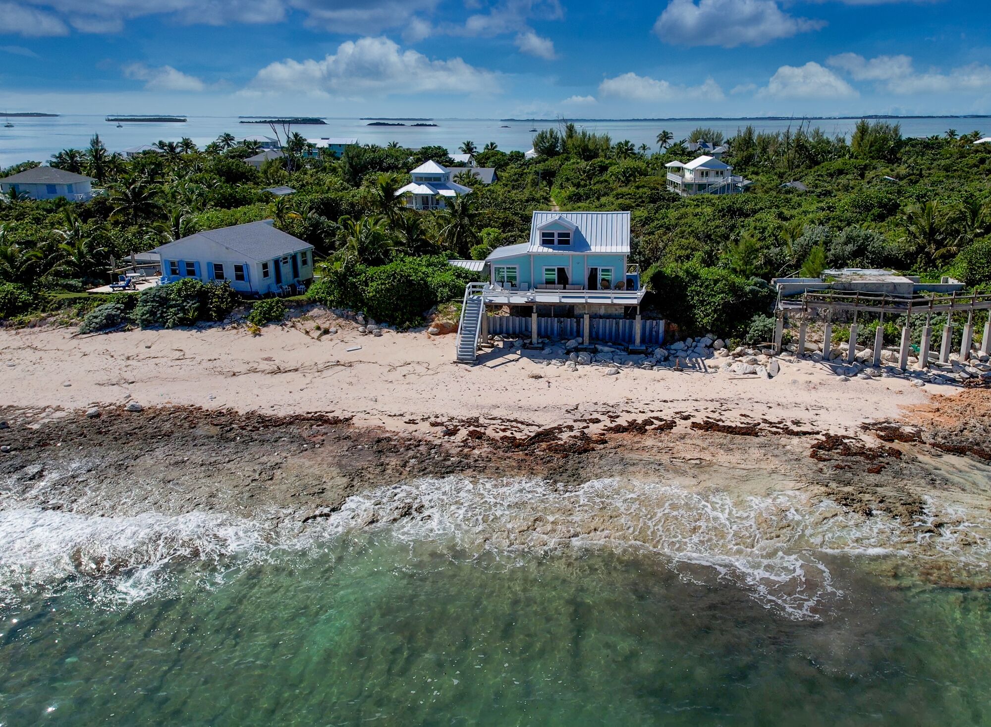 A beachfront property with multiple buildings, clear waters, and boats in the distance.