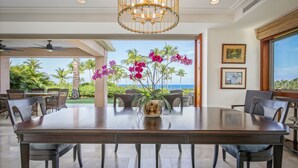 A dining area with a large table, chairs, and a view of the ocean.