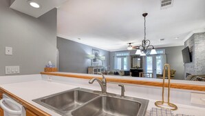 Une cuisine moderne dotée d’un grand îlot central, d’un évier en acier inoxydable et d’un lustre.