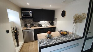 A modern kitchen with a microwave, sink, and dishwasher. There is a decorative vase with flowers on the counter.
