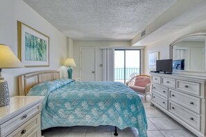 A bedroom with a bed, a dresser, a chair, a TV, and a painting on the wall.