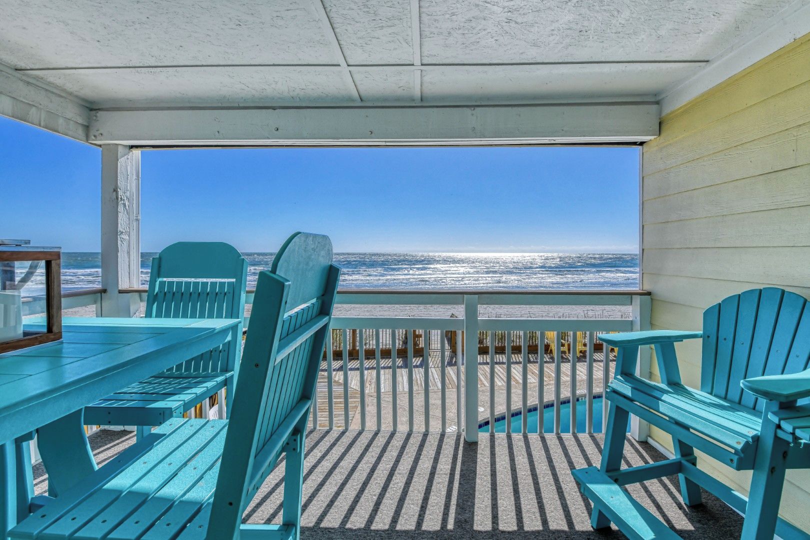 A covered outdoor area with a view of the ocean, featuring a table and chairs.