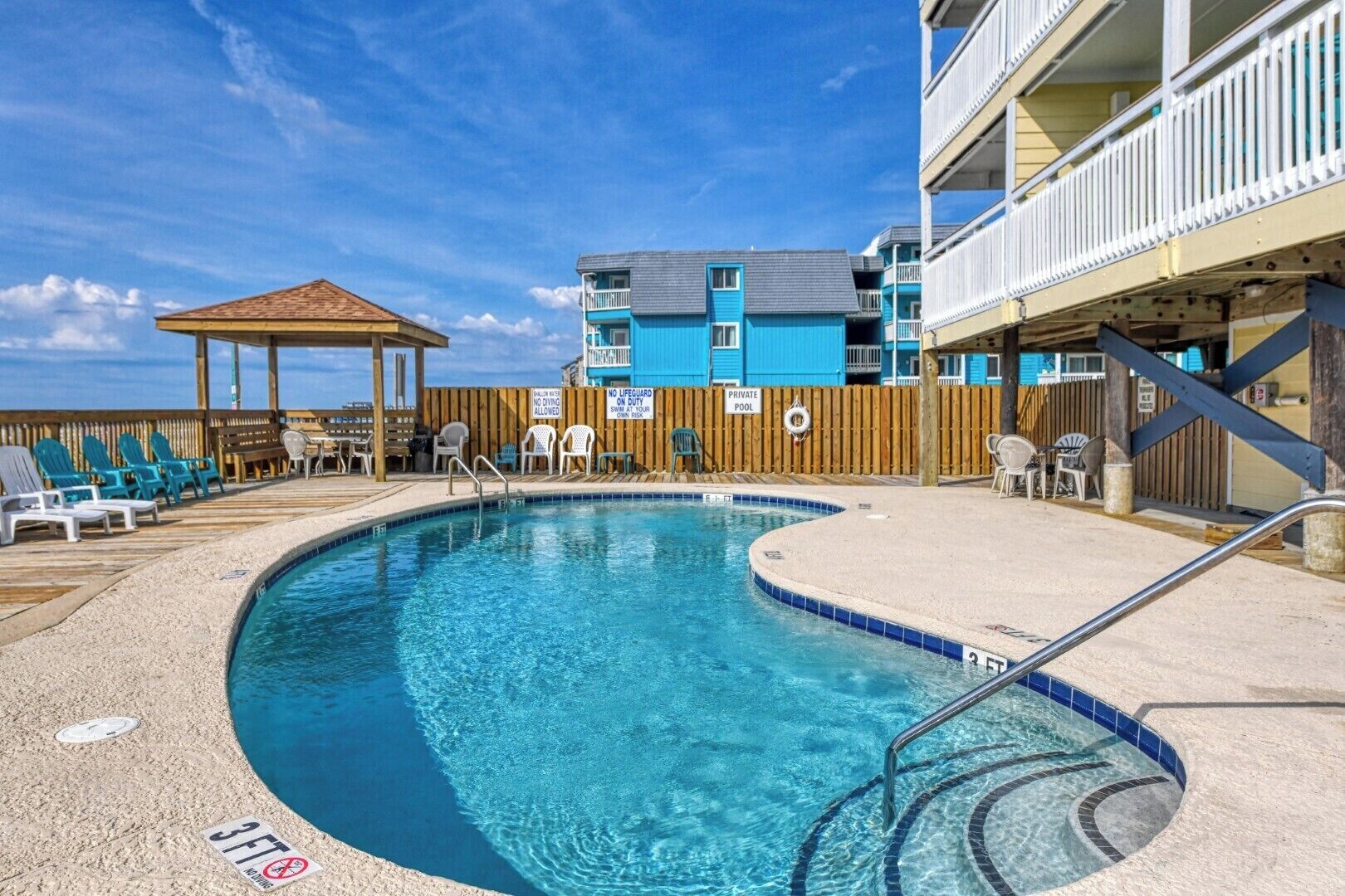 Une piscine privée avec une terrasse en bois, des chaises longues et un kiosque.