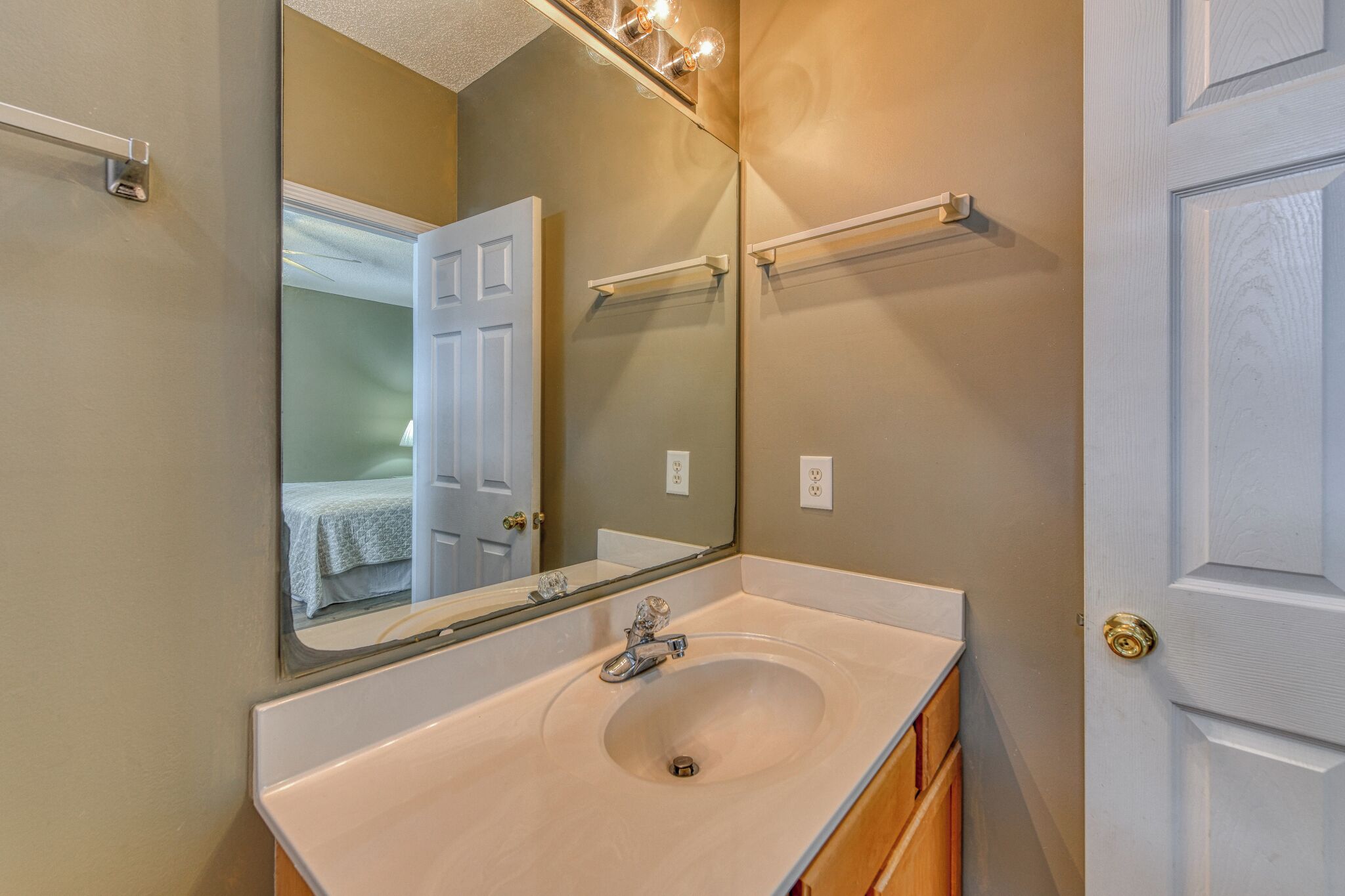 A bathroom with a sink, mirror, and towel rack.