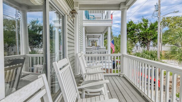 A covered porch with white wooden chairs and a railing. - Better Twin - Five Bedroom, Four 1.5 Bath Beach House with Ocean Views (Surfside Beach)