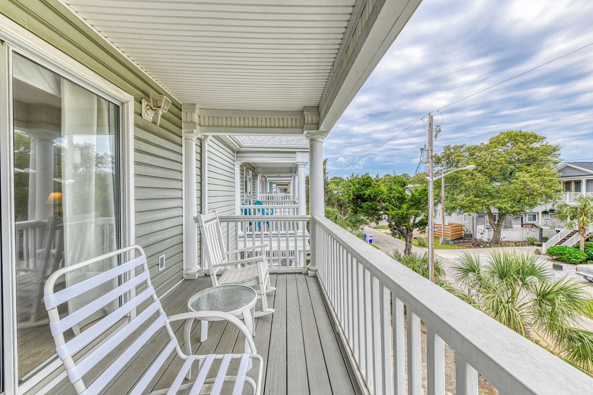 A covered porch with white railings, a table, and chairs.