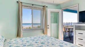 A bedroom with a bed, a window with curtains, a door leading to a balcony, and a TV on a dresser. - Beach House 105 - Two Bedroom, Two Bath Updated Beach Condo (Garden City Beach)