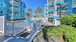 A resort with blue buildings, a pool, and a wooden deck. - Beach House 110, two-bedroom, two-bath ocean-view condo (Garden City Beach)