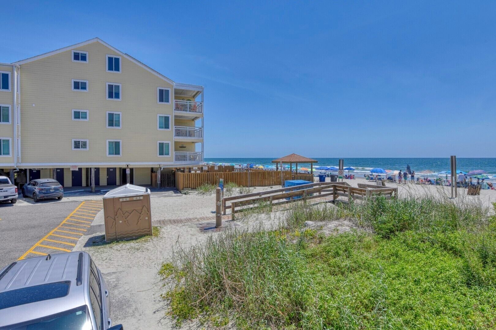 A beachfront hotel with a parking area, a wooden deck, and a beach view.